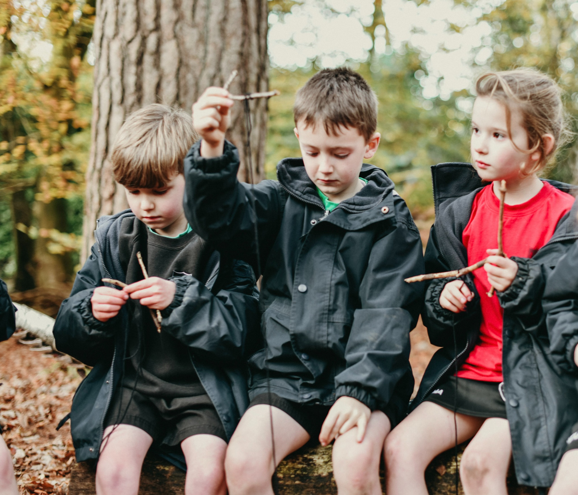 Horris Hill children holding sticks in a Wild Child outdoor learning session