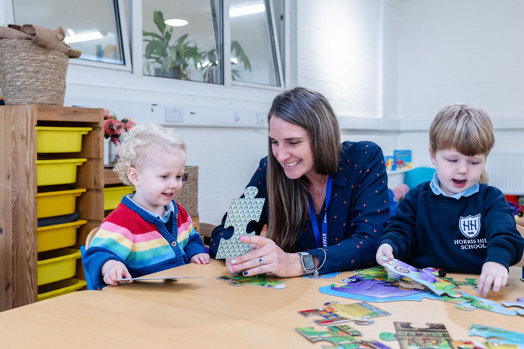 Children playing with puzzle pieces at Horris Hill Nursery