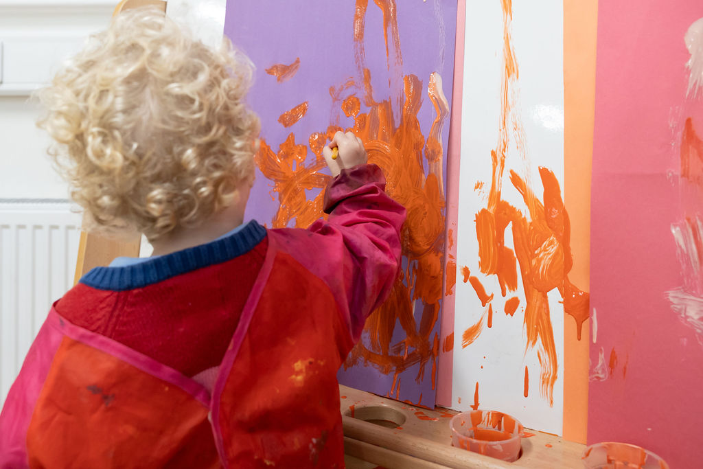 A child in the nursery paints at an art easel